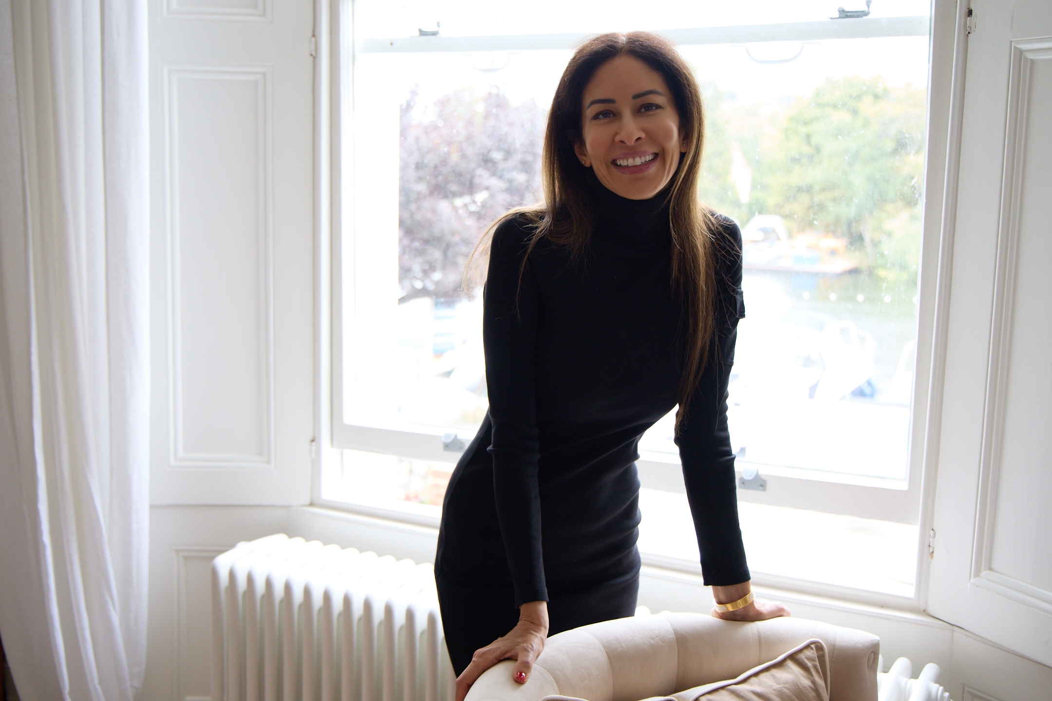Lena Alami standing beside a chair by the window