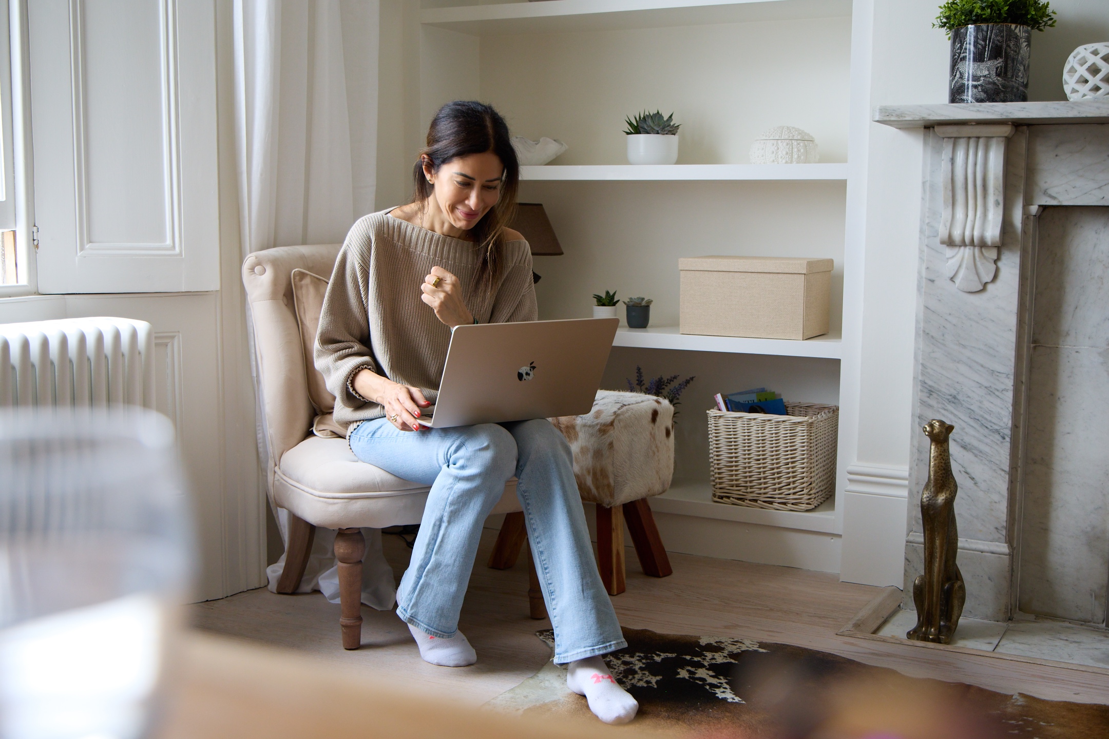 Lena Alami in jeans and a jumper, seated with her laptop